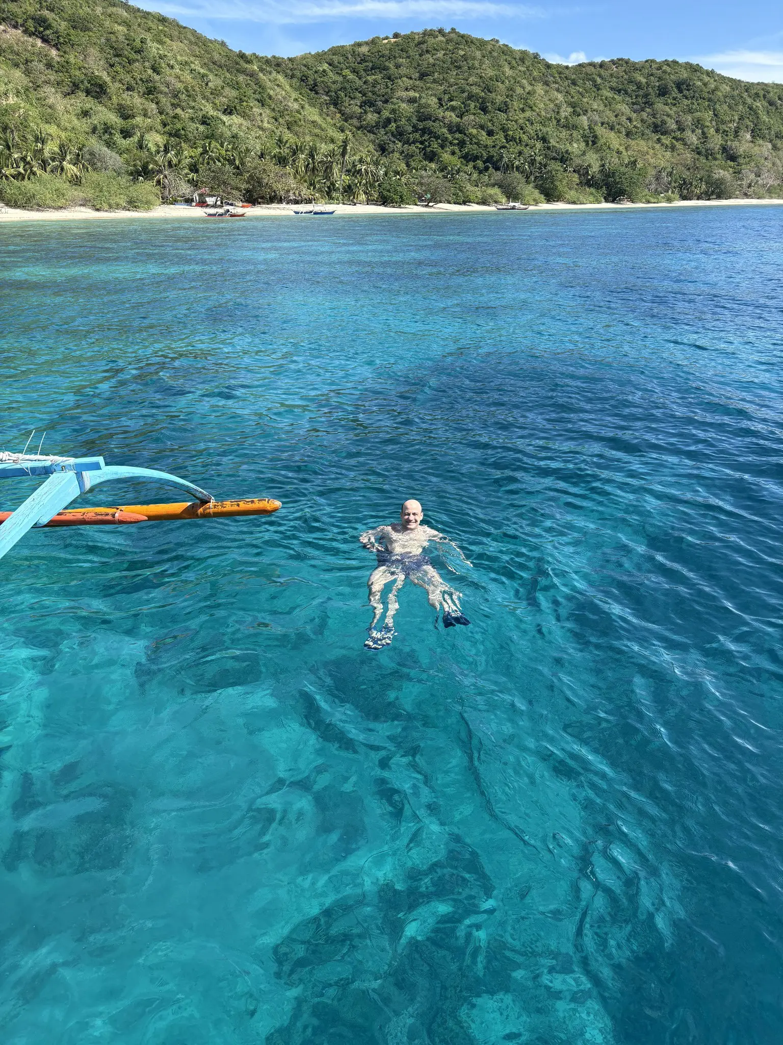 man swimming in clear blue water near a tropical island