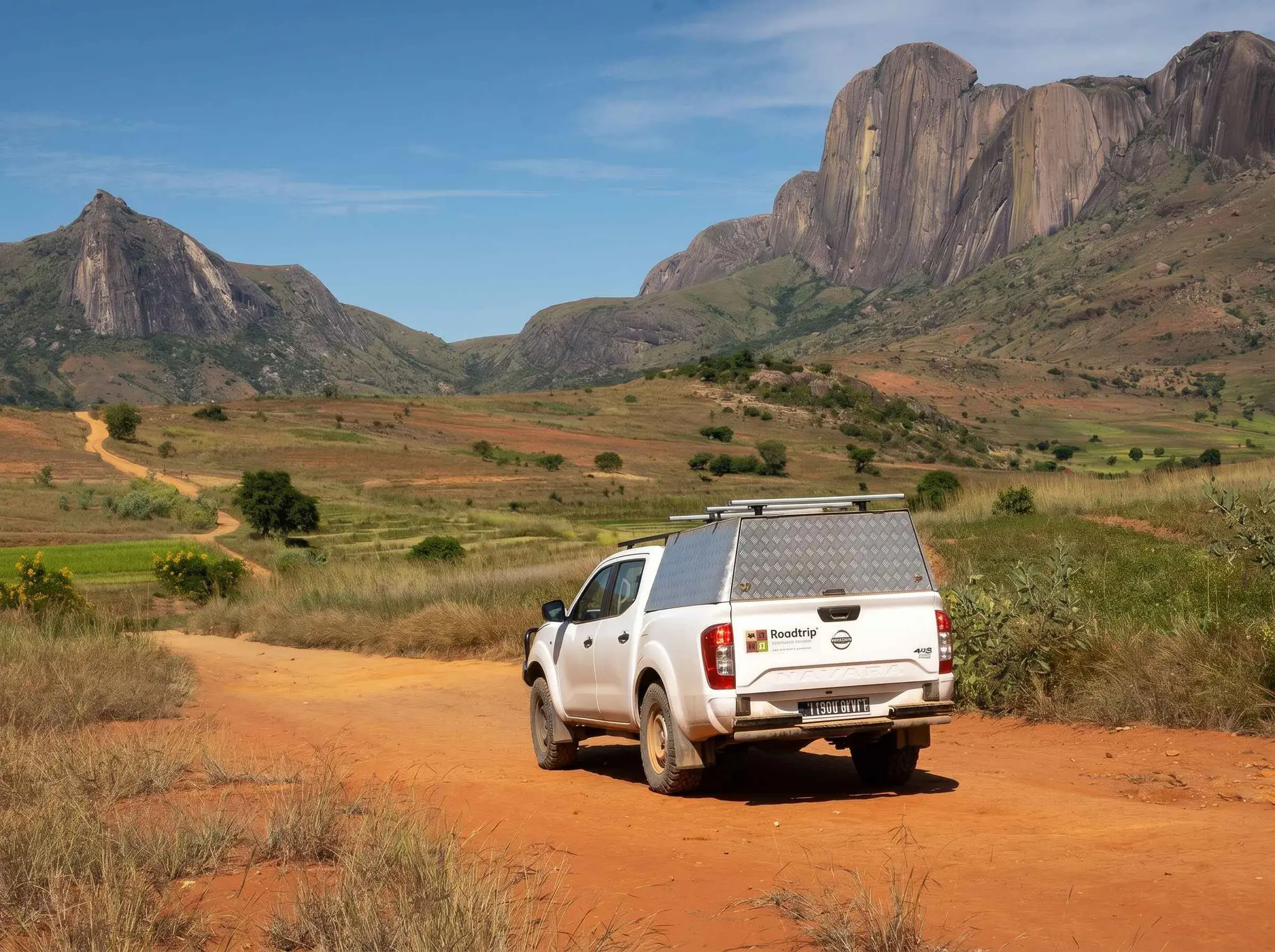 white pickup truck on a dirt road in a mountainous landscape
