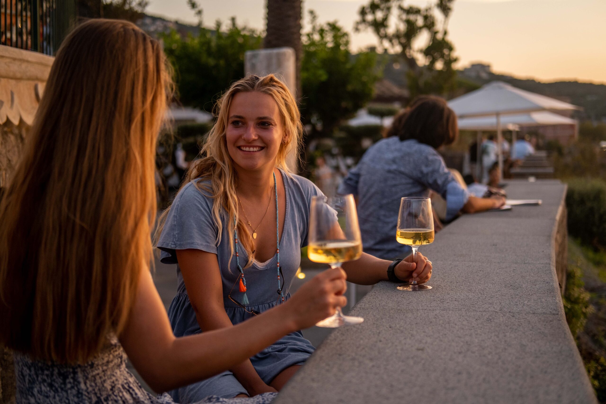 2 girls enjoying a glass of white wine during sunset